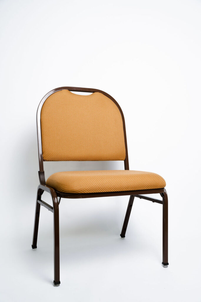 Espaço e Conforto Superiores para o seu Evento A Cadeira Arco Large (modelo CAP-OB) foi desenvolvida pela Tomberlin para espaços que buscam oferecer uma experiência de assento mais ampla e confortável para seus convidados. Ideal para longas jornadas em convenções, auditórios e hotelaria de alto padrão. Diferencial Ergonômico: Espuma de Alta Densidade Para garantir o máximo de conforto do início ao fim do evento, a Arco Large conta com uma estofaria premium: o encosto é fabricado com espuma laminada D28, enquanto o assento é equipado com a super-resistente espuma laminada D45. O revestimento padrão é em tecido 100% poliéster. Estrutura de Alta Performance Fabricada como padrão com estrutura reforçada em aço carbono, a cadeira recebe o exclusivo tratamento nanocerâmico e acabamento em pintura eletrostática a pó. Esses processos garantem extrema proteção contra o desgaste contínuo. Caso a sua operação exija peças mais leves para o manuseio, a estrutura pode ser encomendada em alumínio, o que reduz o peso da cadeira em cerca de 2 kg (nota: cadeiras em alumínio não aceitam o acessório Braço Universitário). Armazenamento Inteligente e Diferenciais Tomberlin Empilhamento Seguro: Sistema estrutural inteligente que garante um grande número de cadeiras empilhadas com segurança e praticidade. Este modelo permite o empilhamento seguro de até 10 unidades. Protetor Lateral: Todos os modelos de cadeiras possuem protetores laterais em plástico injetado, desenhados para evitar danos e arranhões no chassi durante o processo de empilhamento. Sapatas em Policarbonato: O policarbonato é um material mais resistente a atritos e impactos, garantindo mais durabilidade à peça e protegendo o piso do seu salão.