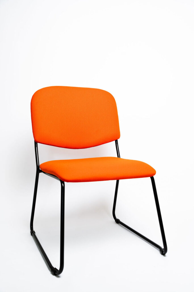 Design Diferenciado e Conforto para Grandes Eventos A Cadeira Mimi CM apresenta uma estrutura com visual moderno e arrojado, ideal para salões de eventos, hotéis e auditórios que buscam fugir do tradicional sem abrir mão da durabilidade. Ela é a escolha perfeita para agregar estética e ergonomia ao seu espaço. Estrutura de Alta Performance Fabricada como padrão com uma estrutura reforçada em aço carbono , a cadeira Mimi CM recebe o exclusivo tratamento nanocerâmico e acabamento em pintura eletrostática a pó. Isso garante proteção máxima contra o desgaste do uso contínuo. Caso a operação exija peças mais leves, a estrutura pode ser fabricada em alumínio, reduzindo o peso em cerca de 2 kg (nota: cadeiras em alumínio não aceitam o acessório Braço Universitário ). Ergonomia e Conforto Prolongado Para garantir que os convidados tenham a melhor experiência, tanto o assento quanto o encosto são desenvolvidos com espuma injetada e revestimento em tecido 100% poliéster. Armazenamento Inteligente e Diferenciais Tomberlin Empilhamento Seguro: O sistema estrutural inteligente permite o empilhamento prático e seguro de até 5 cadeiras. Protetor Lateral: Todos os modelos de cadeiras possuem protetores em plástico injetado nas laterais, desenhados para evitar danos e arranhões no chassi durante o empilhamento. Sapatas em Policarbonato: O policarbonato é mais resistente a atritos e impactos, protegendo o piso e garantindo maior durabilidade à peça.