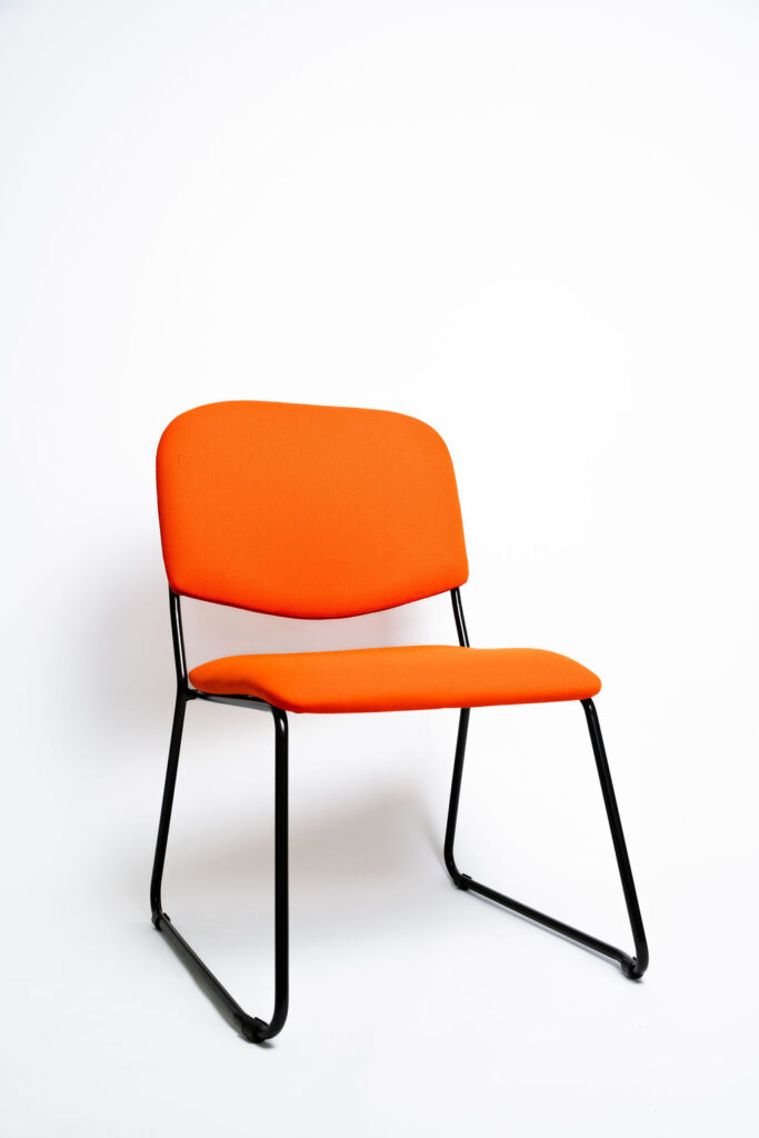 Design Diferenciado e Conforto para Grandes Eventos A Cadeira Mimi CM apresenta uma estrutura com visual moderno e arrojado, ideal para salões de eventos, hotéis e auditórios que buscam fugir do tradicional sem abrir mão da durabilidade. Ela é a escolha perfeita para agregar estética e ergonomia ao seu espaço. Estrutura de Alta Performance Fabricada como padrão com uma estrutura reforçada em aço carbono , a cadeira Mimi CM recebe o exclusivo tratamento nanocerâmico e acabamento em pintura eletrostática a pó. Isso garante proteção máxima contra o desgaste do uso contínuo. Caso a operação exija peças mais leves, a estrutura pode ser fabricada em alumínio, reduzindo o peso em cerca de 2 kg (nota: cadeiras em alumínio não aceitam o acessório Braço Universitário ). Ergonomia e Conforto Prolongado Para garantir que os convidados tenham a melhor experiência, tanto o assento quanto o encosto são desenvolvidos com espuma injetada e revestimento em tecido 100% poliéster. Armazenamento Inteligente e Diferenciais Tomberlin Empilhamento Seguro: O sistema estrutural inteligente permite o empilhamento prático e seguro de até 5 cadeiras. Protetor Lateral: Todos os modelos de cadeiras possuem protetores em plástico injetado nas laterais, desenhados para evitar danos e arranhões no chassi durante o empilhamento. Sapatas em Policarbonato: O policarbonato é mais resistente a atritos e impactos, protegendo o piso e garantindo maior durabilidade à peça.