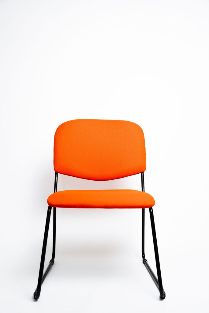 Design Diferenciado e Conforto para Grandes Eventos A Cadeira Mimi CM apresenta uma estrutura com visual moderno e arrojado, ideal para salões de eventos, hotéis e auditórios que buscam fugir do tradicional sem abrir mão da durabilidade. Ela é a escolha perfeita para agregar estética e ergonomia ao seu espaço. Estrutura de Alta Performance Fabricada como padrão com uma estrutura reforçada em aço carbono , a cadeira Mimi CM recebe o exclusivo tratamento nanocerâmico e acabamento em pintura eletrostática a pó. Isso garante proteção máxima contra o desgaste do uso contínuo. Caso a operação exija peças mais leves, a estrutura pode ser fabricada em alumínio, reduzindo o peso em cerca de 2 kg (nota: cadeiras em alumínio não aceitam o acessório Braço Universitário ). Ergonomia e Conforto Prolongado Para garantir que os convidados tenham a melhor experiência, tanto o assento quanto o encosto são desenvolvidos com espuma injetada e revestimento em tecido 100% poliéster. Armazenamento Inteligente e Diferenciais Tomberlin Empilhamento Seguro: O sistema estrutural inteligente permite o empilhamento prático e seguro de até 5 cadeiras. Protetor Lateral: Todos os modelos de cadeiras possuem protetores em plástico injetado nas laterais, desenhados para evitar danos e arranhões no chassi durante o empilhamento. Sapatas em Policarbonato: O policarbonato é mais resistente a atritos e impactos, protegendo o piso e garantindo maior durabilidade à peça.