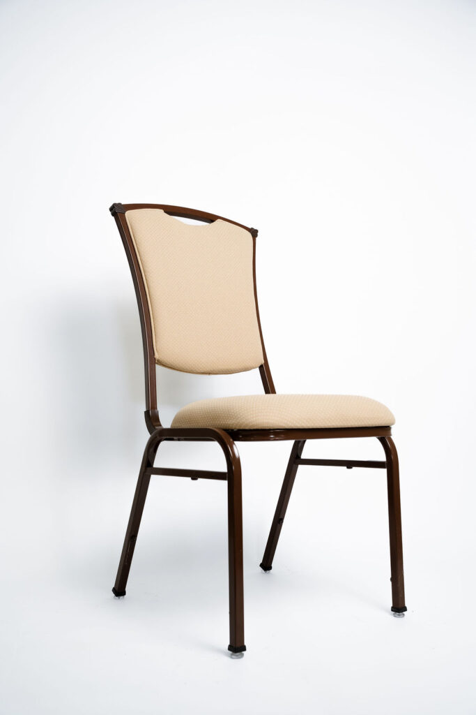 Sofisticação e Robustez para Grandes Eventos A Cadeira Safira CF da Tomberlin foi projetada para atender às altas exigências do mercado de hotéis e eventos. Com um design elegante, ela garante não apenas o conforto visual e físico dos convidados, mas também um excelente retorno sobre o investimento devido à sua durabilidade superior ao tempo. Estrutura de Alta Performance Fabricada com estrutura reforçada em aço carbono , a cadeira recebe um exclusivo tratamento nanocerâmico e acabamento em pintura eletrostática a pó. Esses processos garantem máxima proteção contra o desgaste diário. Para projetos que exigem maior leveza no manuseio, a estrutura padrão em aço carbono pode ser substituída por alumínio , o que reduz o peso da peça em média 2 kg. Conforto Prolongado Pensando no bem-estar durante palestras, casamentos e convenções, o assento e o encosto são desenvolvidos com espuma injetada e revestidos em tecido 100% poliéster. Armazenamento Inteligente e Diferenciais Tomberlin Empilhamento Seguro: Sistema inteligente que garante um grande número de cadeiras empilhadas com segurança e praticidade , permitindo pilhas de até 10 unidades para este modelo. Protetor Lateral: Todos os modelos possuem protetores em plástico injetado nas laterais , desenhados especificamente para evitar danos no empilhamento. Sapatas em Policarbonato: O policarbonato é mais resistente a atritos e impactos , garantindo mais durabilidade à peça.